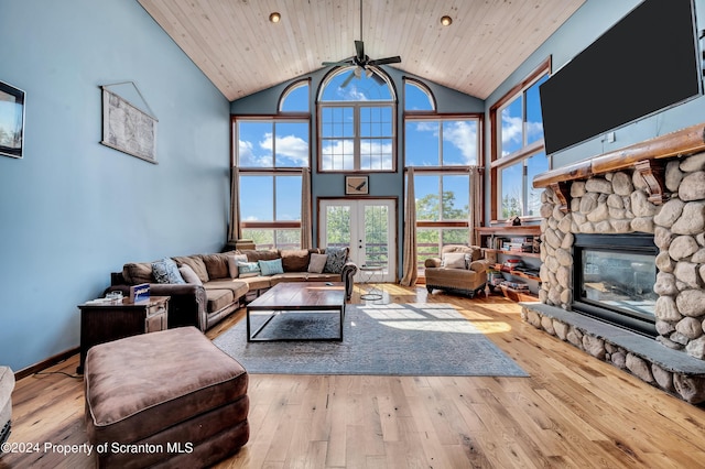 living room featuring french doors, wooden ceiling, a stone fireplace, light hardwood / wood-style flooring, and high vaulted ceiling