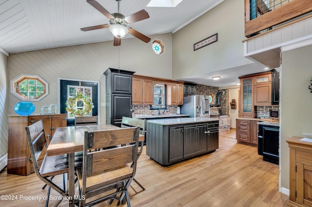 kitchen featuring a skylight, stainless steel appliances, light hardwood / wood-style flooring, backsplash, and a kitchen island