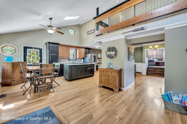 kitchen with stainless steel fridge with ice dispenser, backsplash, a kitchen island, ceiling fan with notable chandelier, and light wood-type flooring