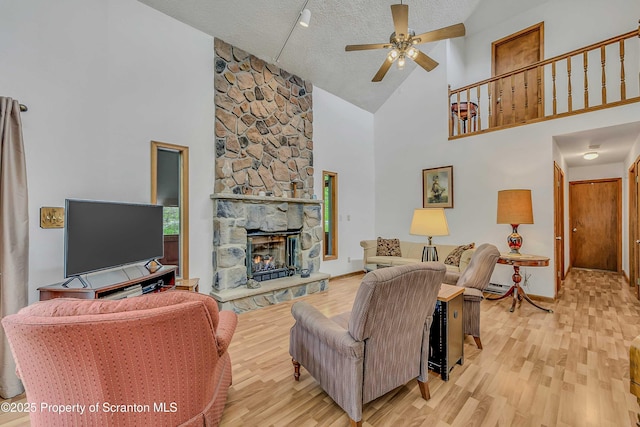 582 Lakeview Dr W, Lake Ariel, PA 18436 - living room featuring high vaulted ceiling, a ceiling fan, light wood-style flooring, a fireplace, and a textured ceiling