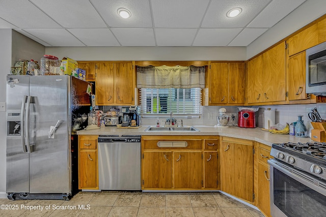 506 N Sumner Ave, Scranton, PA 18504 - kitchen with appliances with stainless steel finishes, light countertops, decorative backsplash, a paneled ceiling, and brown cabinetry
