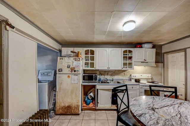 kitchen featuring white appliances, white cabinets, ornamental molding, light tile patterned floors, and washer / dryer