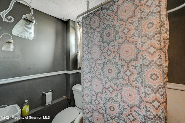 bathroom with toilet and a drop ceiling