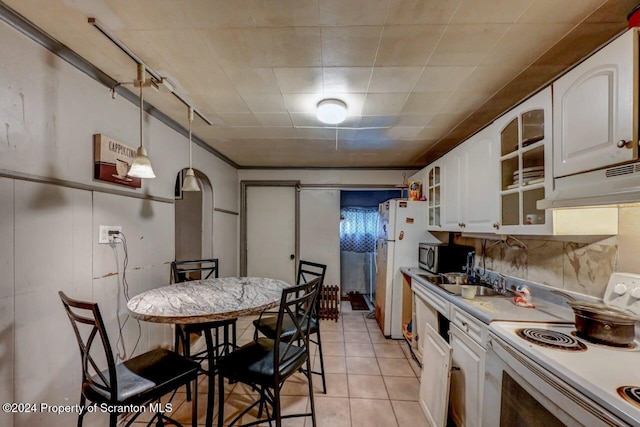 kitchen with white appliances, sink, light tile patterned floors, decorative light fixtures, and white cabinetry