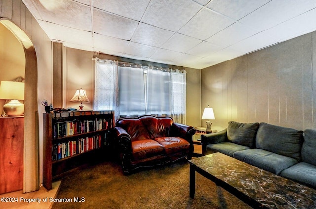 sitting room featuring carpet flooring, a paneled ceiling, and wooden walls