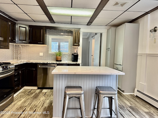 918 Hemlock St, Scranton, PA 18505 - kitchen featuring stainless steel appliances, a sink, baseboard heating, a kitchen bar, and light wood-style floors