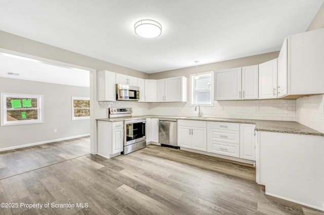 14 Maiden Ln, Susquehanna, PA 18847 - kitchen with stainless steel appliances, a sink, decorative backsplash, light wood-style floors, and white cabinets
