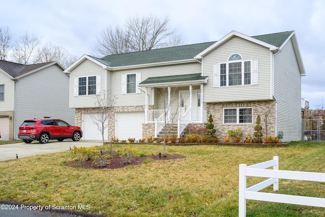 bi-level home with covered porch, a front yard, and a garage