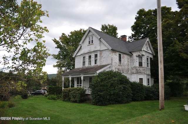 view of property exterior with covered porch, a lawn, and a chimney