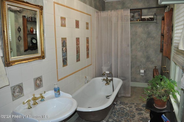 full bathroom with a freestanding bath, tile walls, and a sink