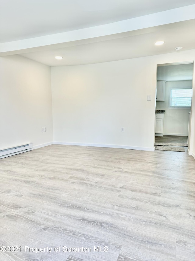 spare room with a baseboard heating unit and light wood-type flooring