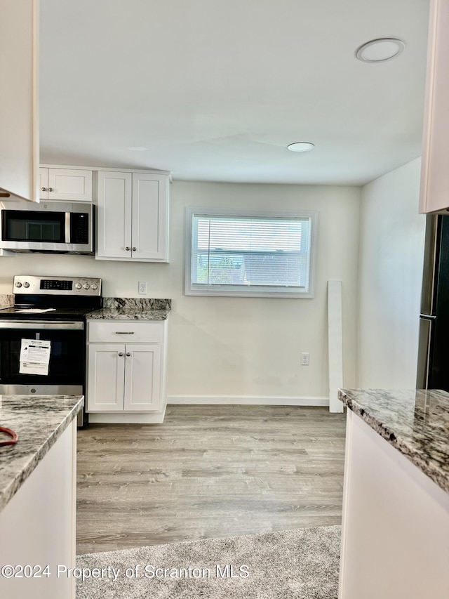 kitchen featuring light stone countertops, white cabinetry, and appliances with stainless steel finishes