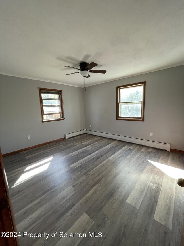 unfurnished room with dark hardwood / wood-style floors, baseboard heating, ceiling fan, and ornamental molding