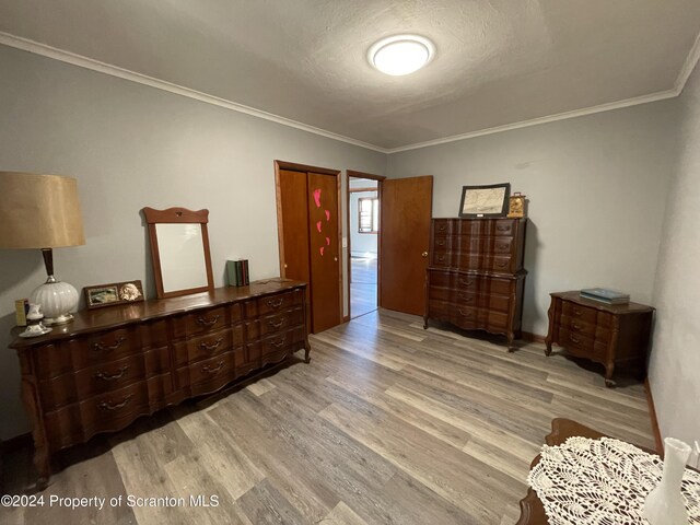 bedroom with crown molding, light hardwood / wood-style floors, and a textured ceiling