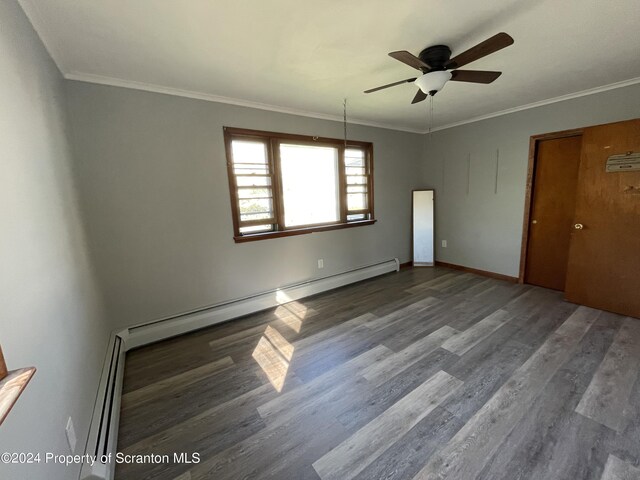 empty room featuring hardwood / wood-style floors, crown molding, and a baseboard heating unit