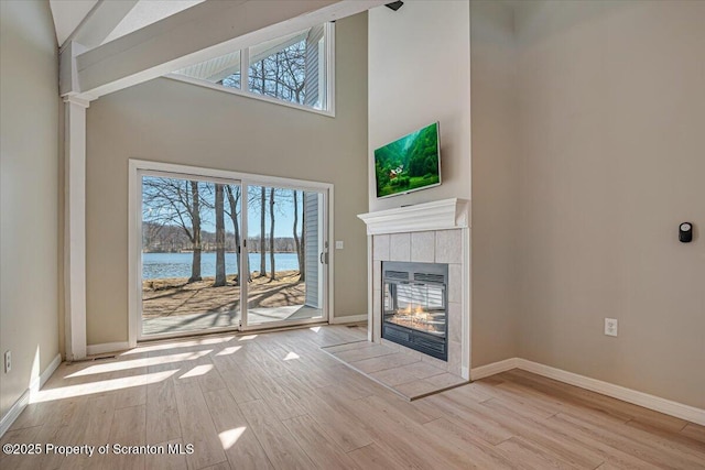 134 Laurel Hill Dr Unit 102, Greentown, PA 18426 - unfurnished living room featuring wood finished floors, a tiled fireplace, healthy amount of natural light, and high vaulted ceiling