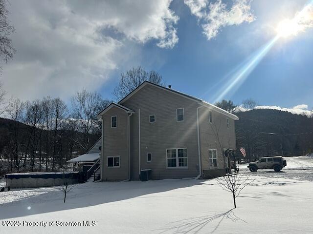 snow covered house with a mountain view and central AC