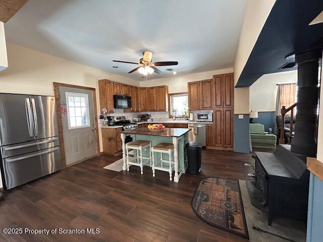 kitchen featuring a kitchen island, a wood stove, a breakfast bar area, and appliances with stainless steel finishes