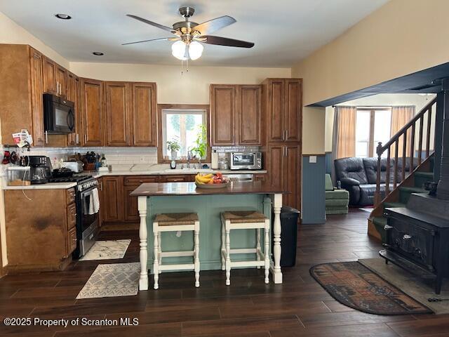 kitchen featuring tasteful backsplash, dark wood-type flooring, stainless steel range with gas stovetop, and a kitchen bar