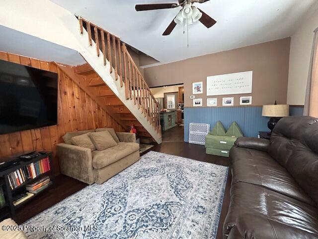 living room with wooden walls, dark hardwood / wood-style floors, and ceiling fan