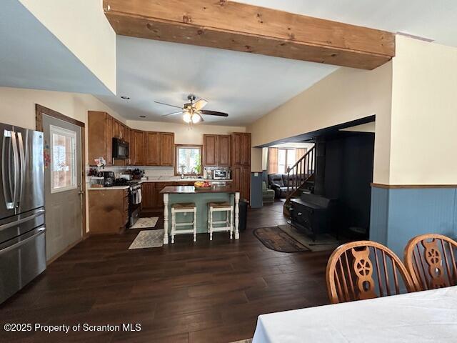 dining room with ceiling fan, dark hardwood / wood-style floors, and beam ceiling