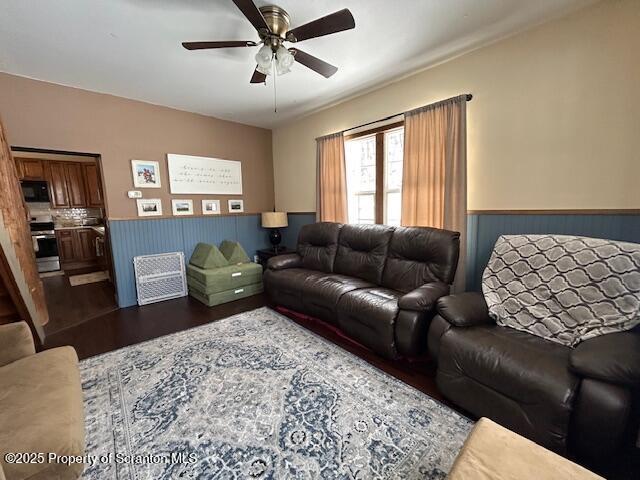 living room with dark wood-type flooring and ceiling fan