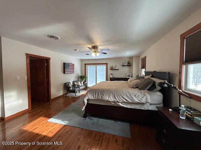 bedroom with multiple windows, hardwood / wood-style floors, and ceiling fan