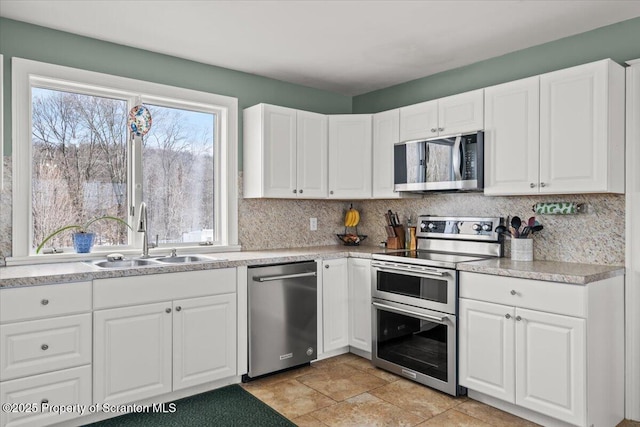 kitchen with sink, backsplash, white cabinets, and stainless steel appliances