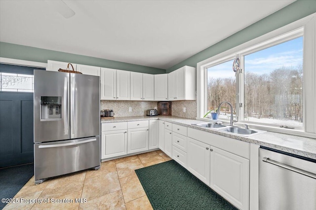 kitchen featuring white cabinets, decorative backsplash, stainless steel appliances, and sink