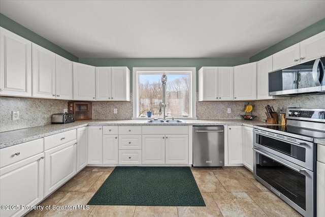 kitchen featuring white cabinets, stainless steel appliances, backsplash, and sink