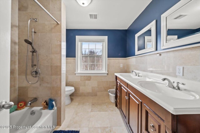 full bathroom with tiled shower / bath combo, toilet, tile walls, tile patterned floors, and vanity