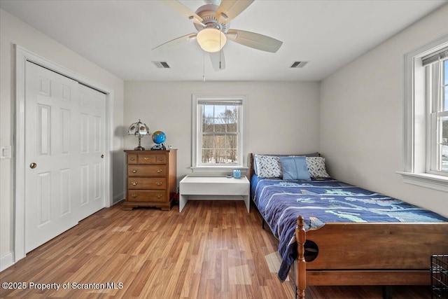 bedroom with light hardwood / wood-style floors, a closet, ceiling fan, and multiple windows