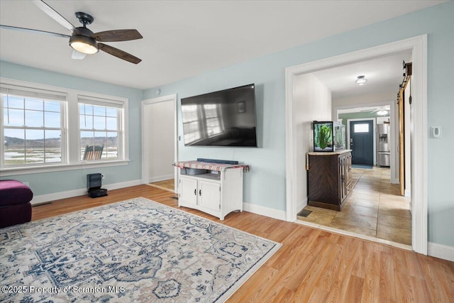 living room with ceiling fan and light hardwood / wood-style flooring