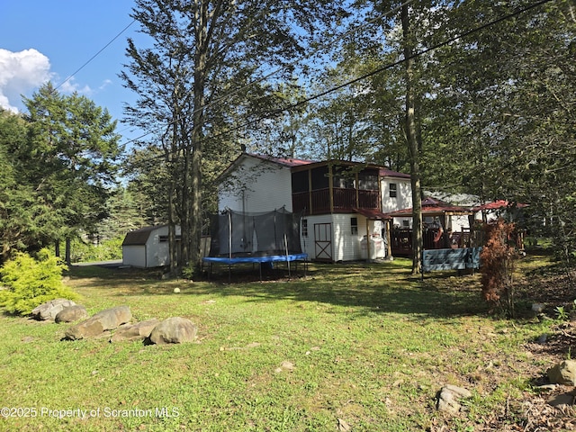 view of yard featuring a trampoline, a sunroom, and a storage unit