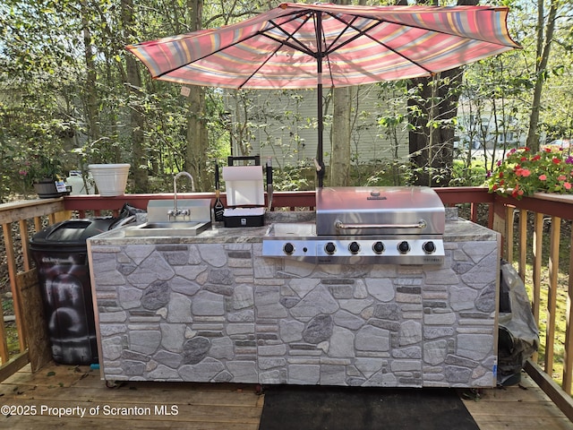 view of patio / terrace with grilling area, sink, a wooden deck, and an outdoor kitchen