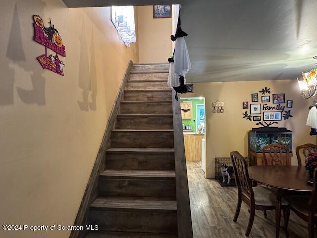 stairway with an inviting chandelier and hardwood / wood-style flooring