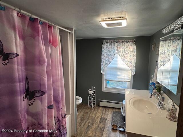 bathroom featuring walk in shower, baseboard heating, toilet, vanity, and hardwood / wood-style flooring