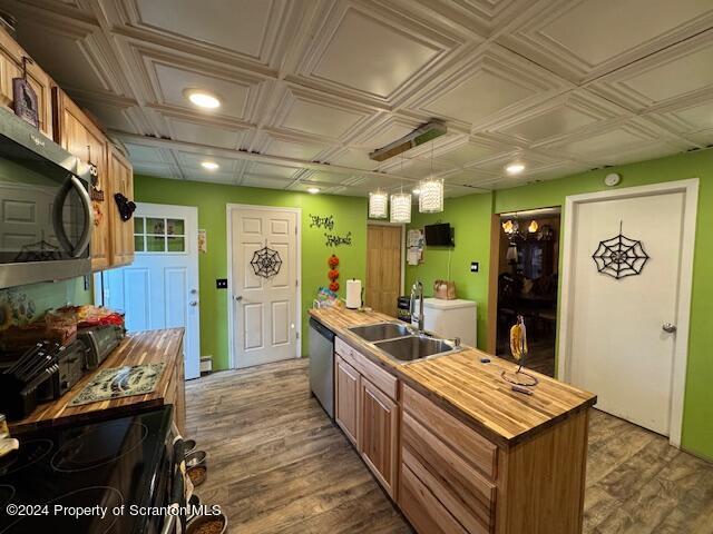 kitchen featuring sink, dark wood-type flooring, hanging light fixtures, an island with sink, and appliances with stainless steel finishes