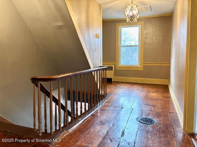 staircase featuring radiator heating unit and a chandelier