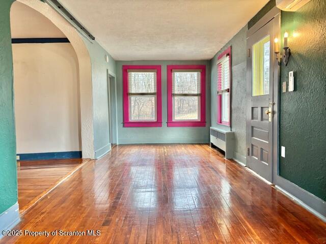 empty room with hardwood / wood-style flooring and radiator heating unit