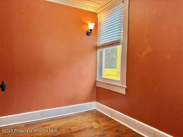 empty room featuring crown molding and hardwood / wood-style flooring