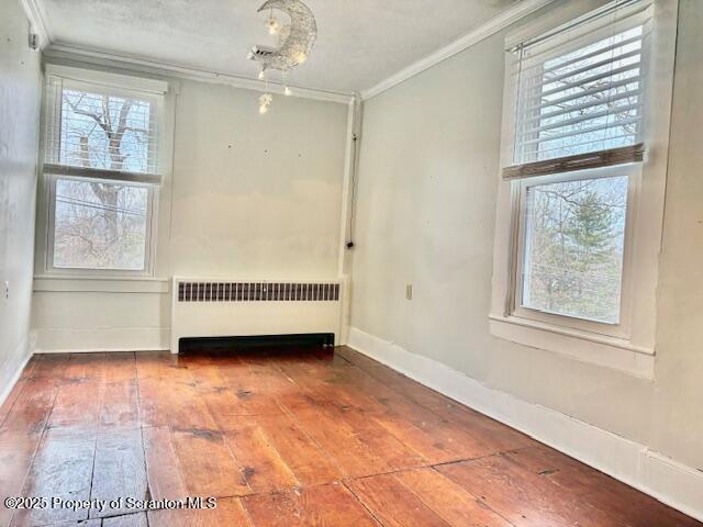 empty room with radiator, crown molding, and hardwood / wood-style floors