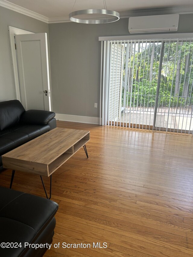 living room with light wood-type flooring, an AC wall unit, and ornamental molding