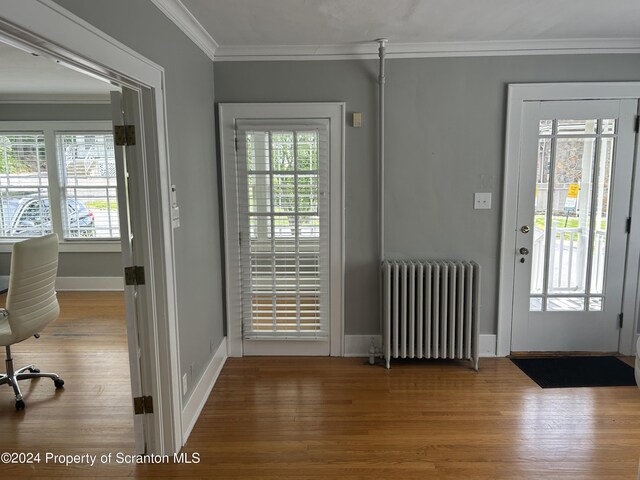 doorway featuring radiator heating unit, hardwood / wood-style flooring, and crown molding