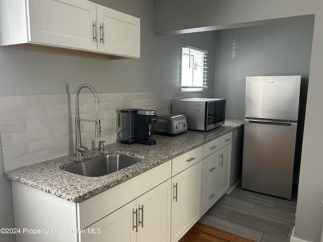 kitchen with white cabinetry, sink, light stone countertops, decorative backsplash, and appliances with stainless steel finishes