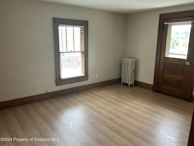 spare room featuring radiator heating unit and light wood-type flooring