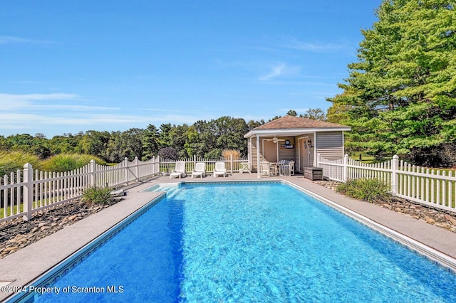 view of swimming pool featuring an outbuilding, a patio, and ceiling fan