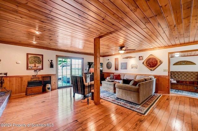 living room with ceiling fan, light hardwood / wood-style floors, wooden ceiling, and wooden walls