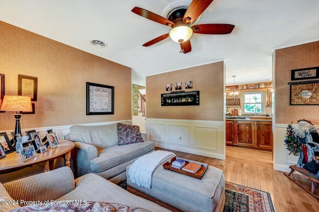 living room featuring light hardwood / wood-style floors and ceiling fan with notable chandelier