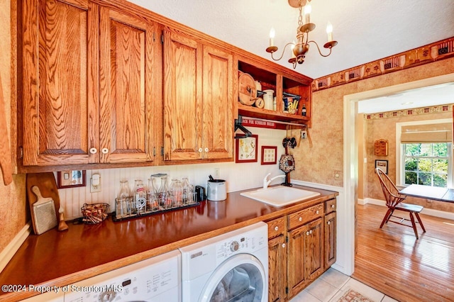 laundry room featuring sink, cabinets, a chandelier, light tile patterned floors, and washer and dryer